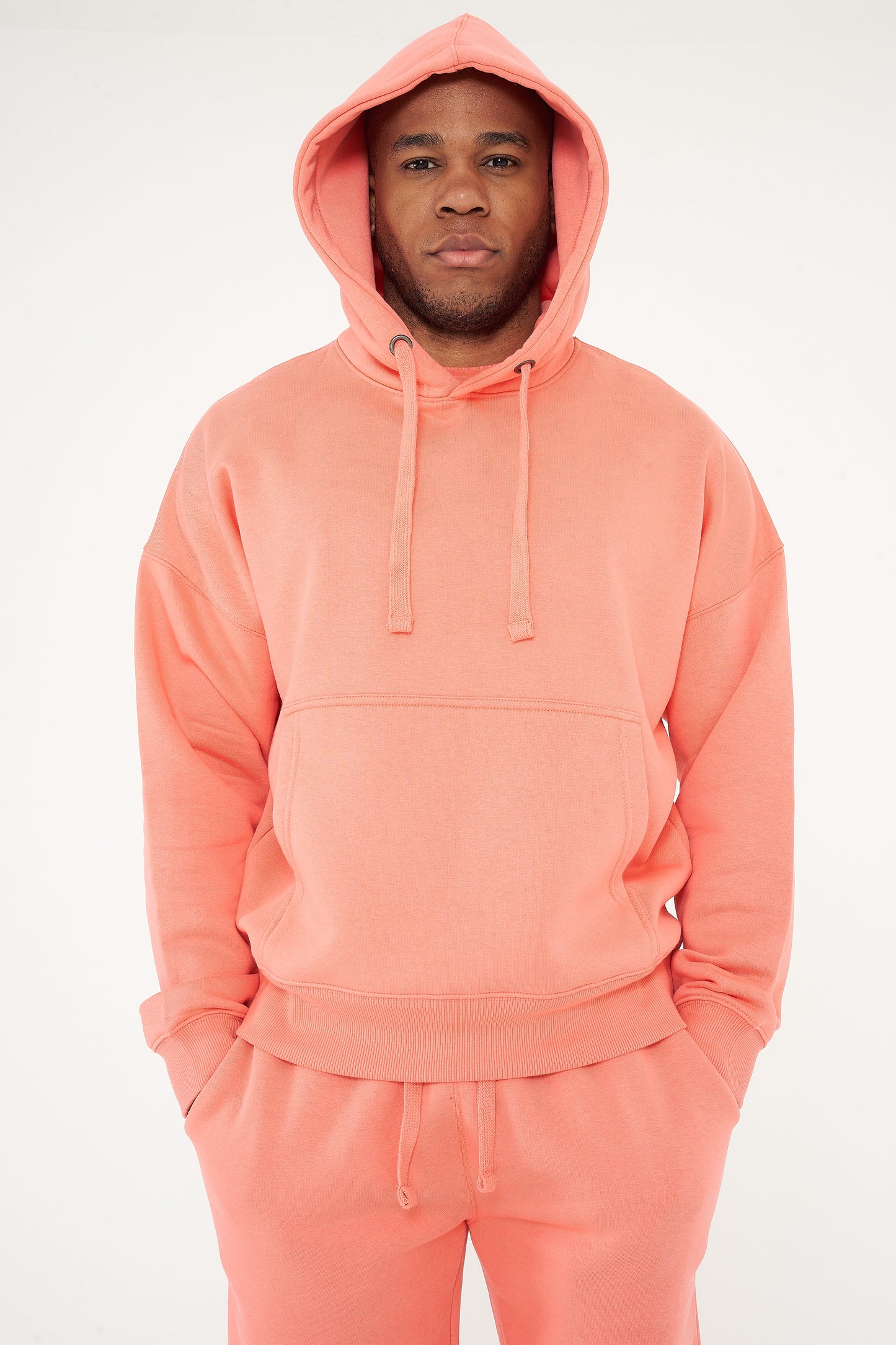 Male model full-body shot in coral 365 Oversized Hoodie and shorts, styled with white sneakers – 365 Collection – oversized fit.