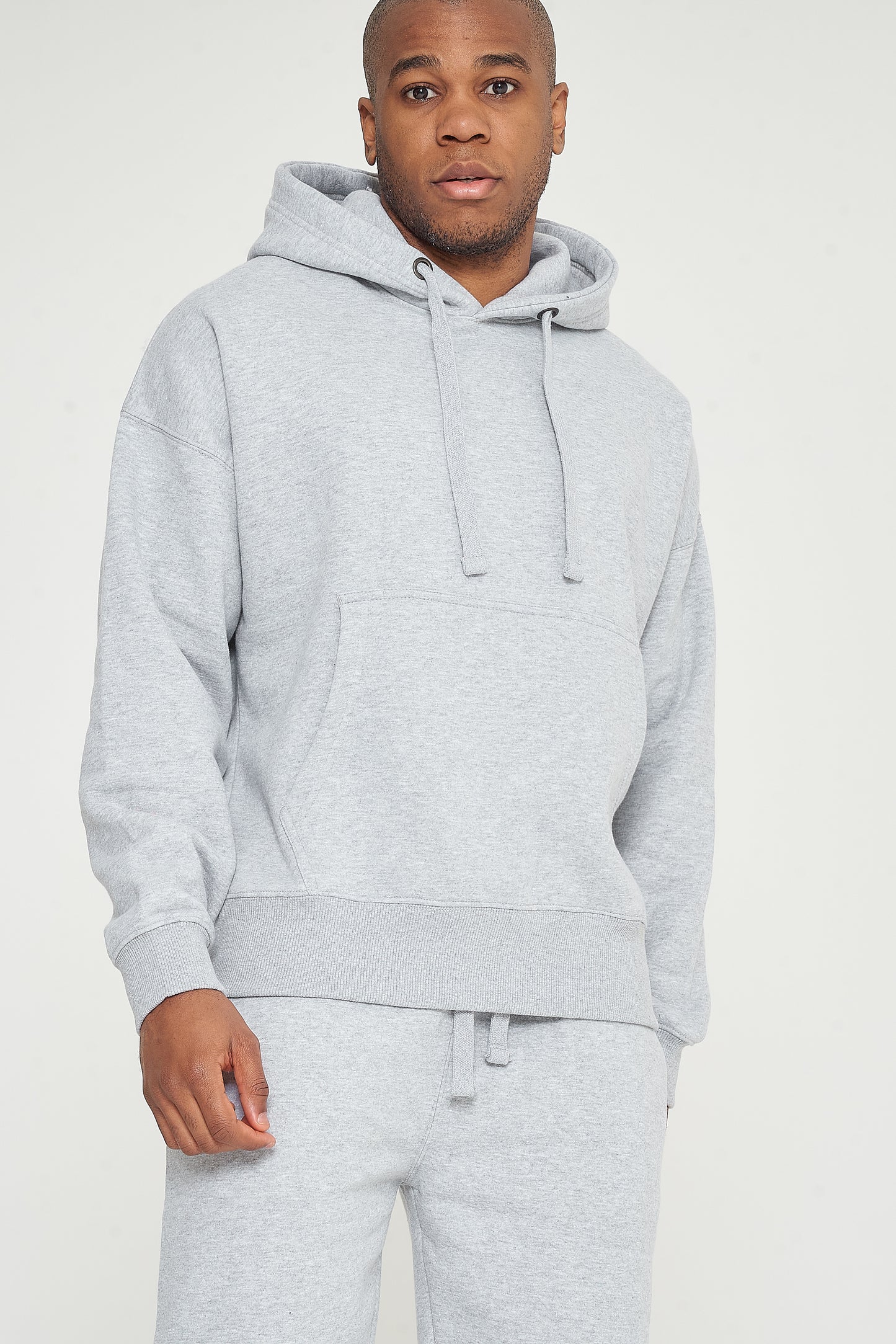 Upper body view of model wearing grey oversized hoodie with hands in pocket - 365 Collection.