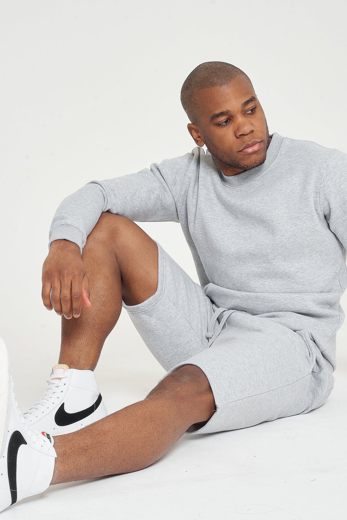 Model seated on the floor wearing a grey regular-fit sweatshirt - 365 Collection.