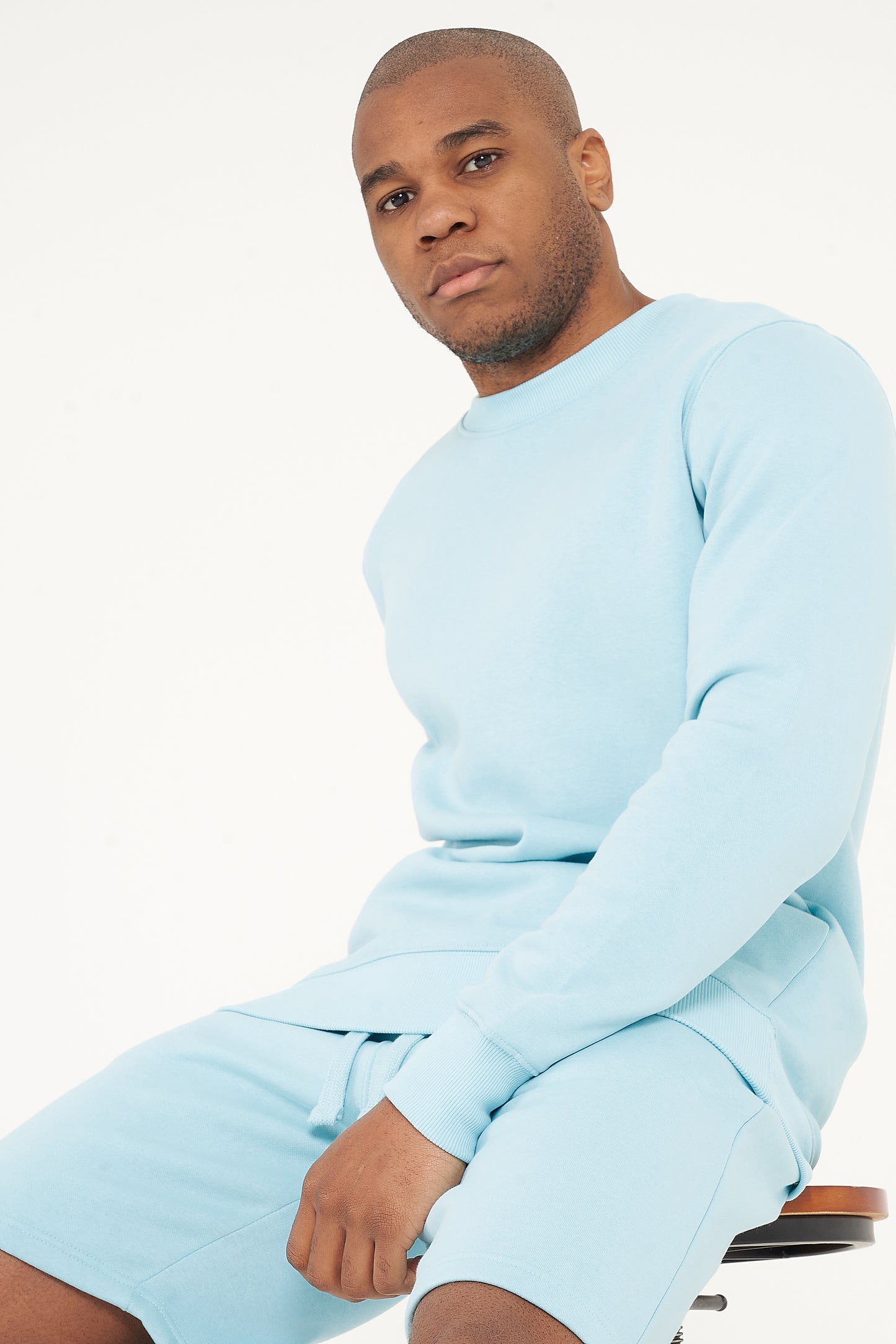 Model sitting and looking sideways in turquoise regular-fit sweatshirt - 365 Collection.