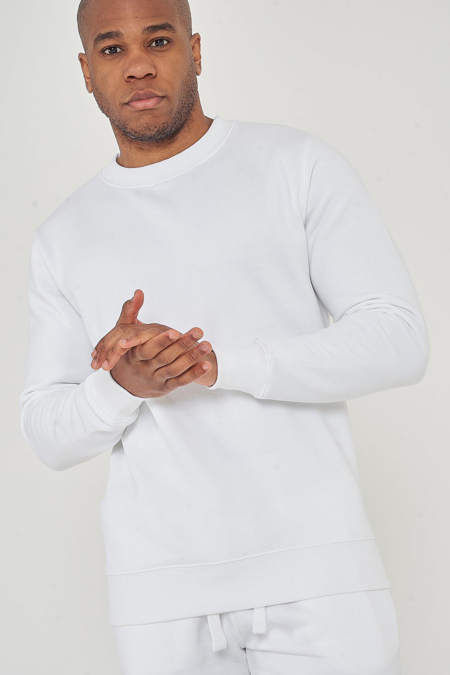 Upper-body front view of male model wearing white oversized sweatshirt with hands clasped – 365 Collection.