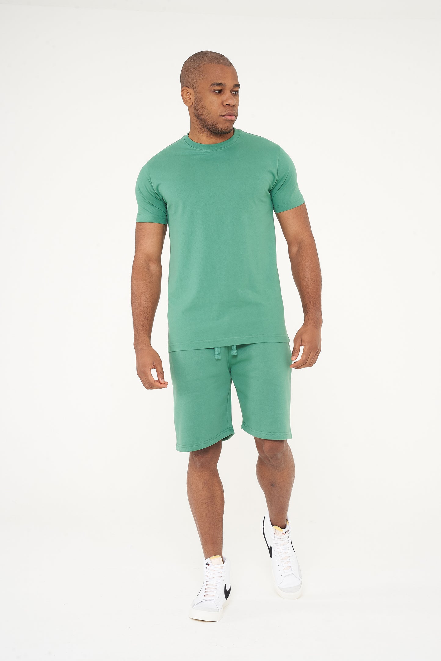 Side view of male model in green regular fit T-shirt and shorts, showing comfort and fit - 365 Collection.
