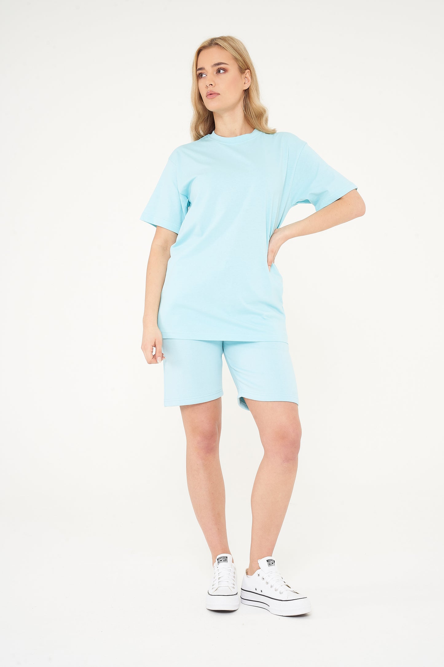 Woman modeling a turquoise oversized t-shirt from the side, highlighting the roomy fit.