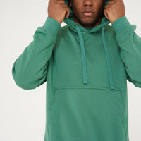 Male model adjusting hood on green oversized hoodie and shorts - 365 Collection.
