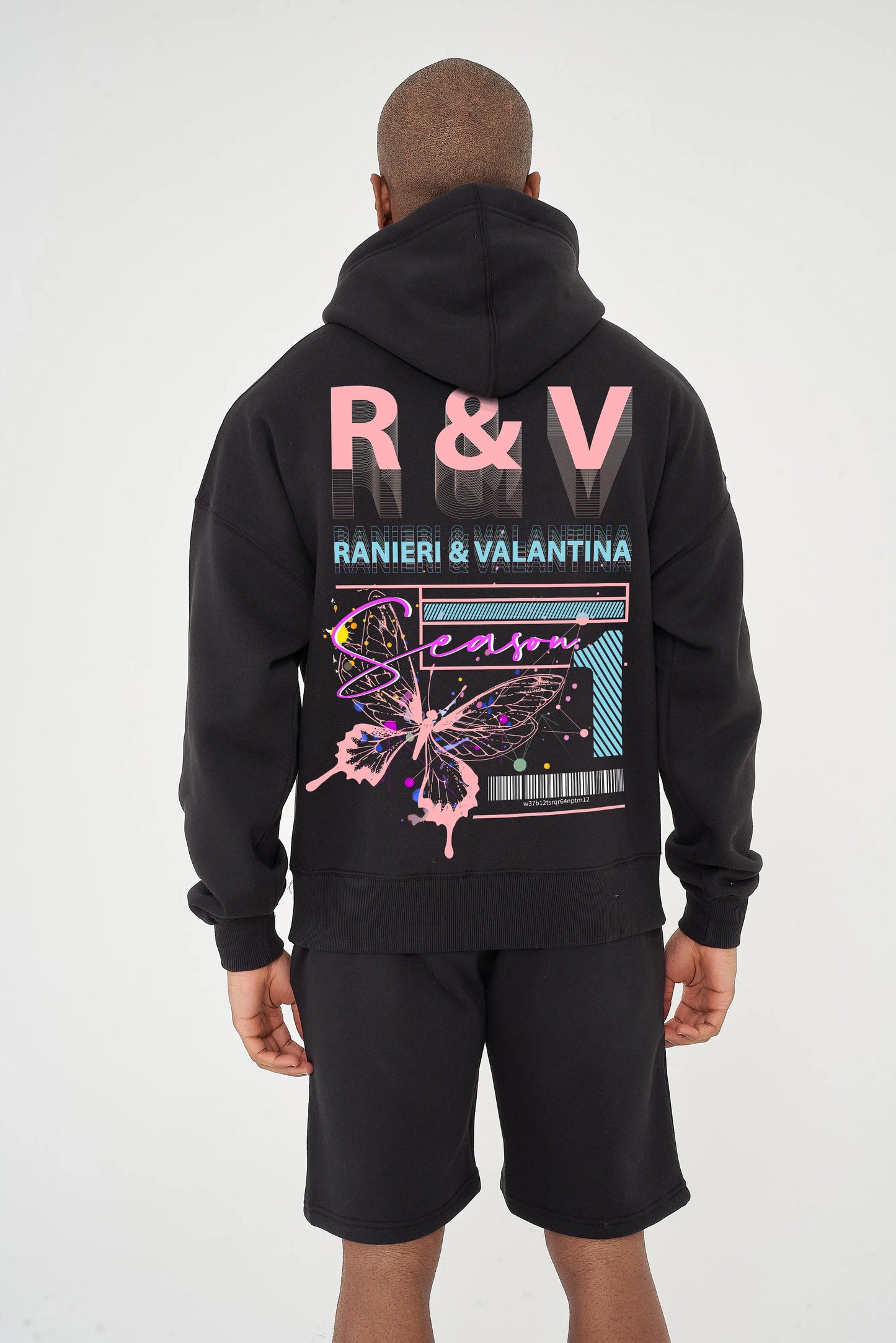Rear view of male model wearing black oversized hoodie with coral butterfly graphic and R&V print – oversized fit.