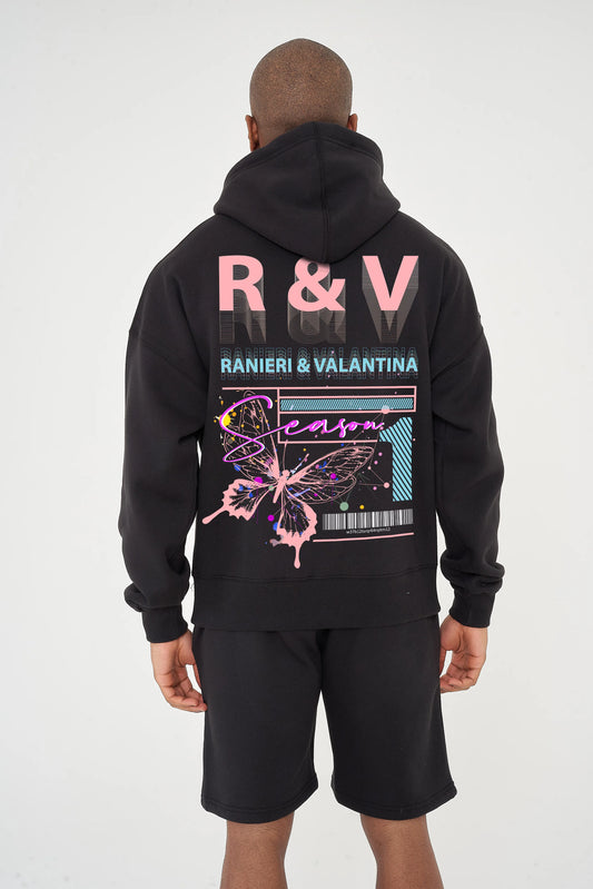 Rear view of male model wearing black oversized hoodie with coral butterfly graphic and R&V print – oversized fit.