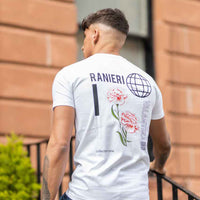 Urban fashion image showing a model outdoors in blue jeans and a white Ranieri Valantina t-shirt, featuring graphic globe and pink floral prints on the back - a contemporary design for streetwear and branded apparel collections.
