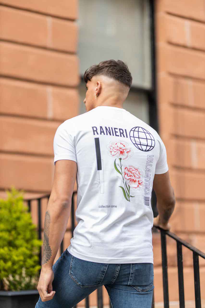 Urban fashion image showing a model outdoors in blue jeans and a white Ranieri Valantina t-shirt, featuring graphic globe and pink floral prints on the back - a contemporary design for streetwear and branded apparel collections.