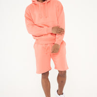Male model front view wearing coral 365 Oversized Hoodie and matching shorts, hands relaxed – 365 Collection – oversized fit. 