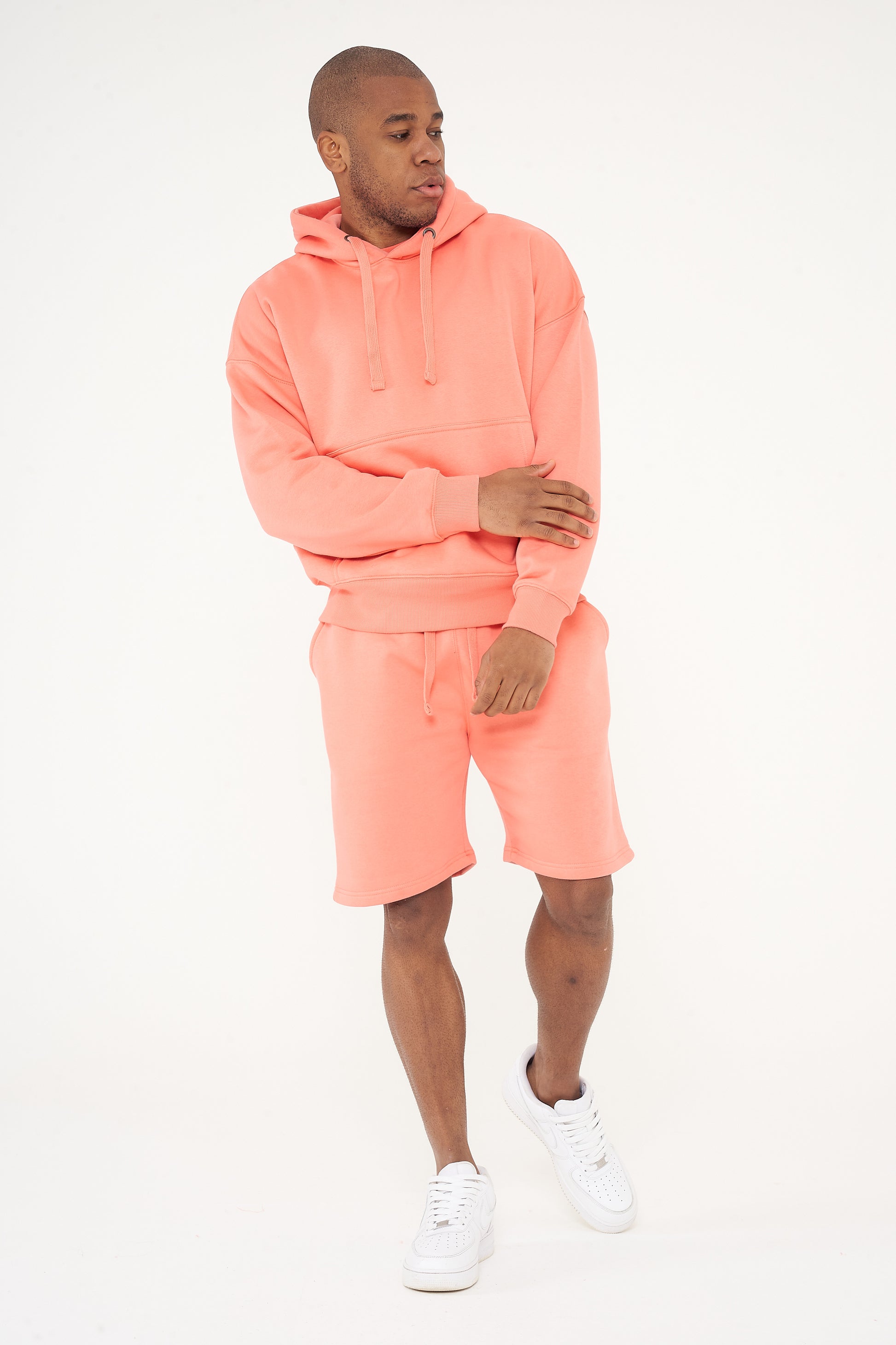 Male model front view wearing coral 365 Oversized Hoodie and matching shorts, hands relaxed – 365 Collection – oversized fit. 