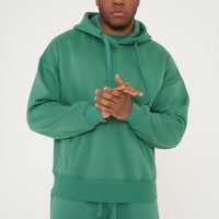 Male model front-facing in green oversized hoodie and shorts, hands relaxed - 365 Collection.
