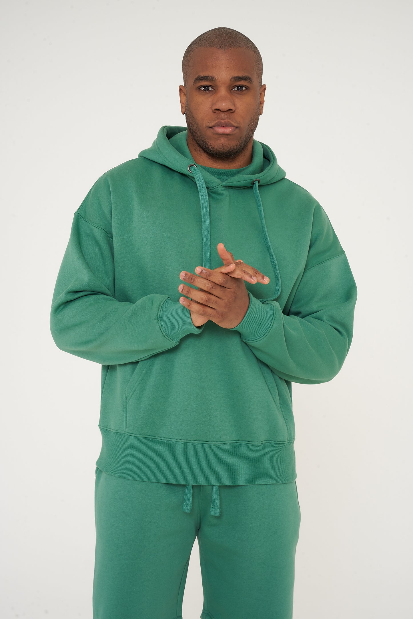 Male model front-facing in green oversized hoodie and shorts, hands relaxed - 365 Collection.