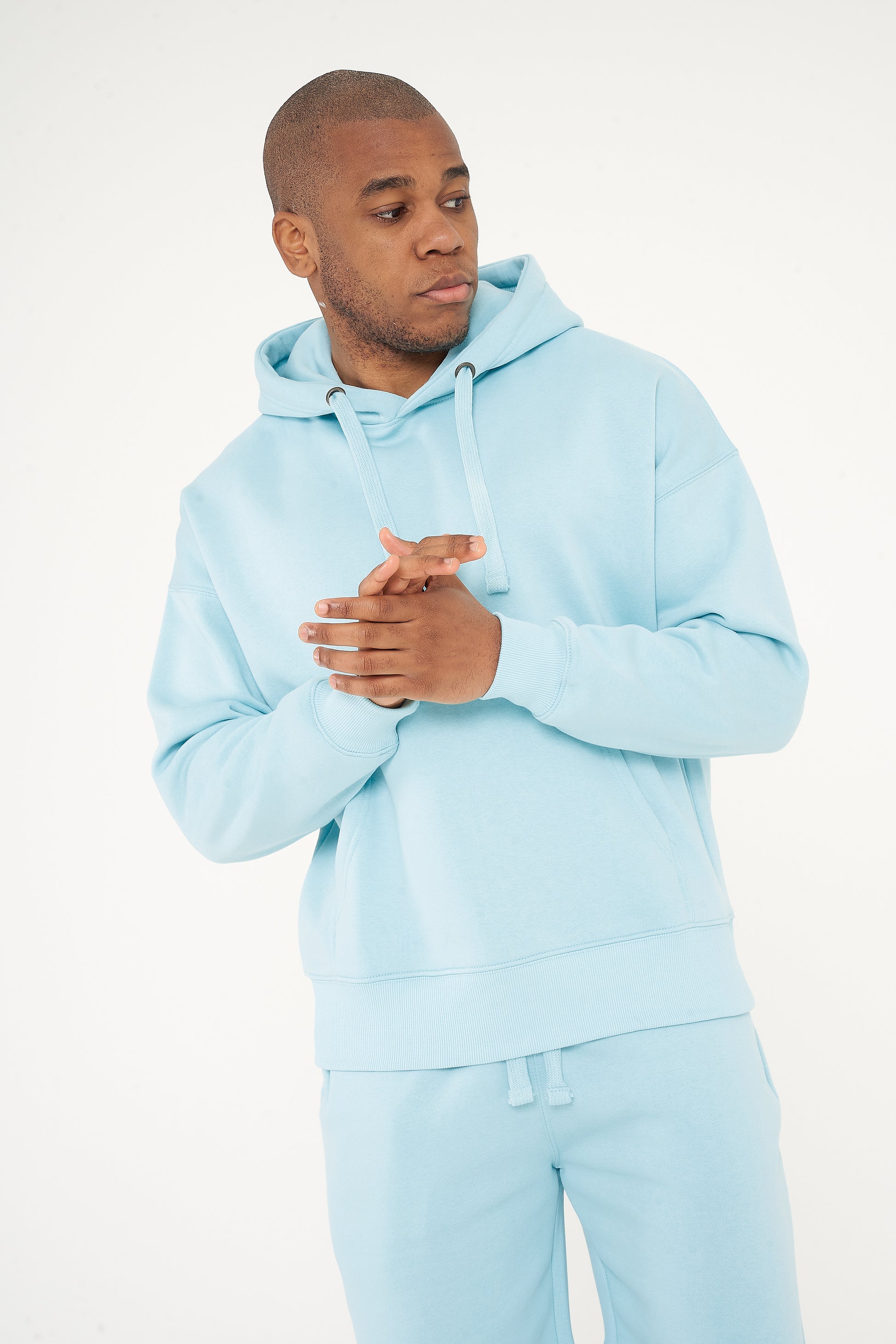 Model posing with clasped hands in turquoise oversized hoodie - 365 Collection.