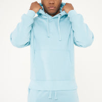 Model adjusting hood in turquoise oversized hoodie - 365 Collection.