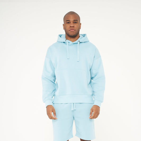 Full-body front view of model wearing men’s turquoise oversized hoodie - 365 Collection. 