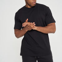 Male model adjusting sleeves in black 365 Oversized T-shirt and shorts – oversized fit, 365 Collection. 