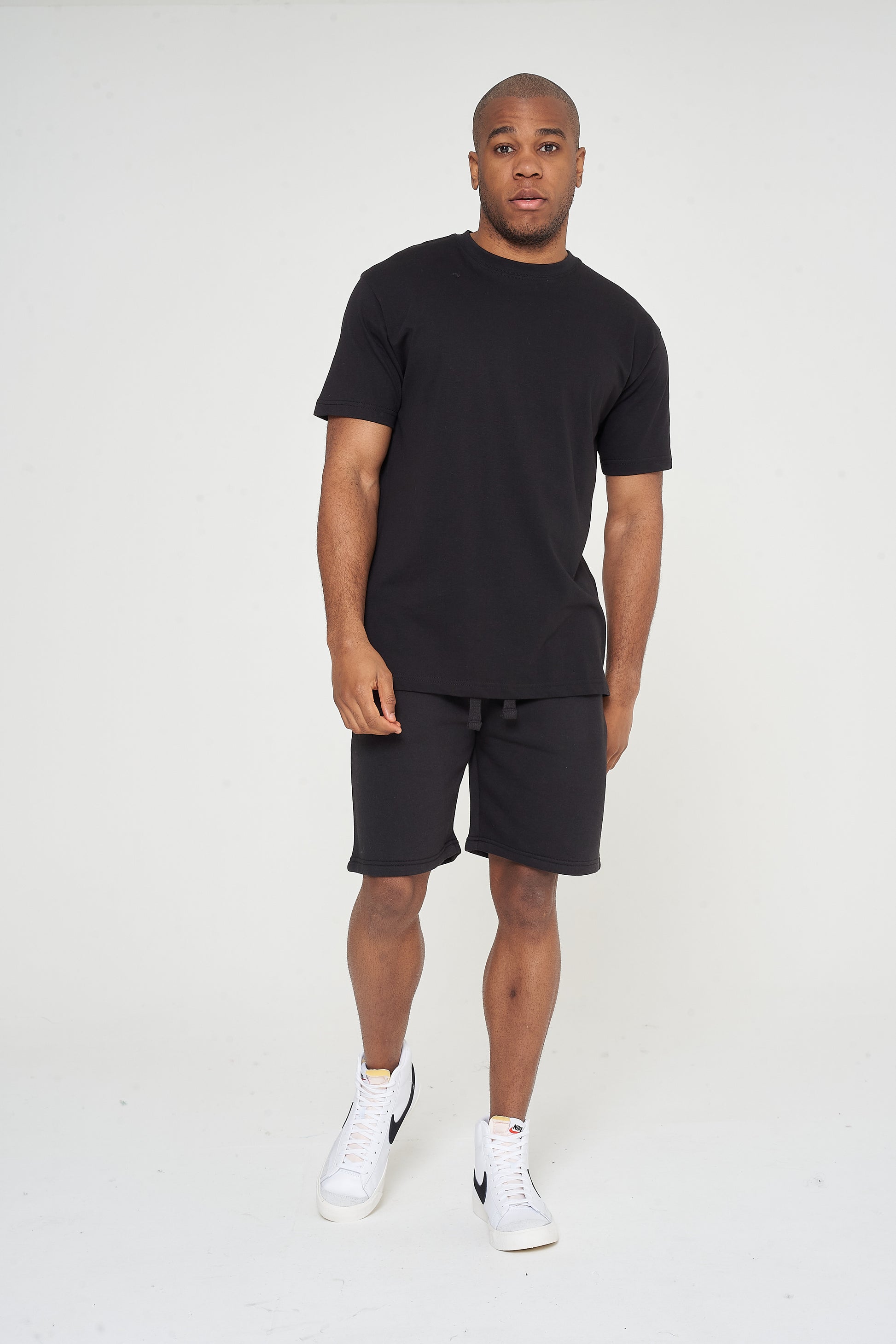 Male model standing in a black 365 Oversized T-shirt and shorts, hands relaxed – oversized fit, 365 Collection. 