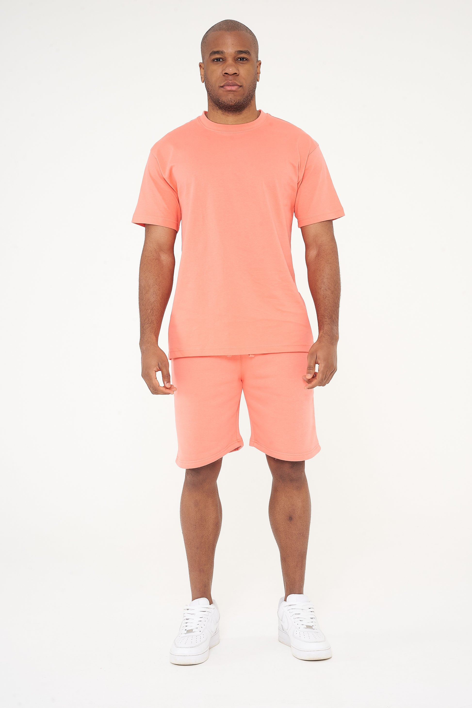 Male model full-body shot in coral 365 Oversized T-shirt and shorts, white sneakers – 365 Collection – oversized fit.