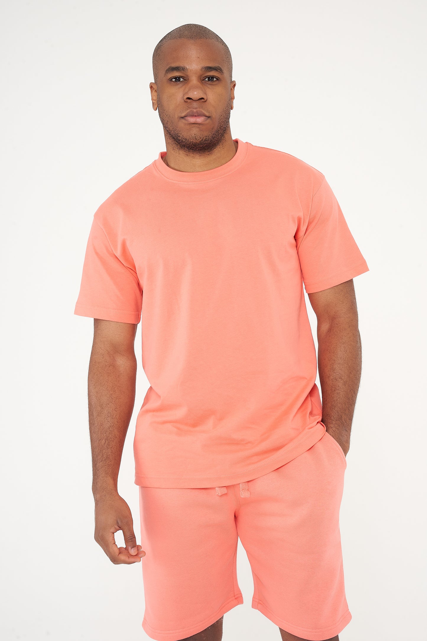 Male model front view wearing coral 365 Oversized T-shirt and matching shorts, hands relaxed – 365 Collection – oversized fit.