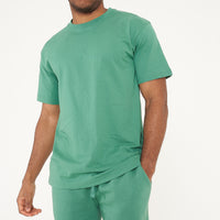 Side view of a male model in green oversized T-shirt and shorts, displaying relaxed fit - 365 Collection.