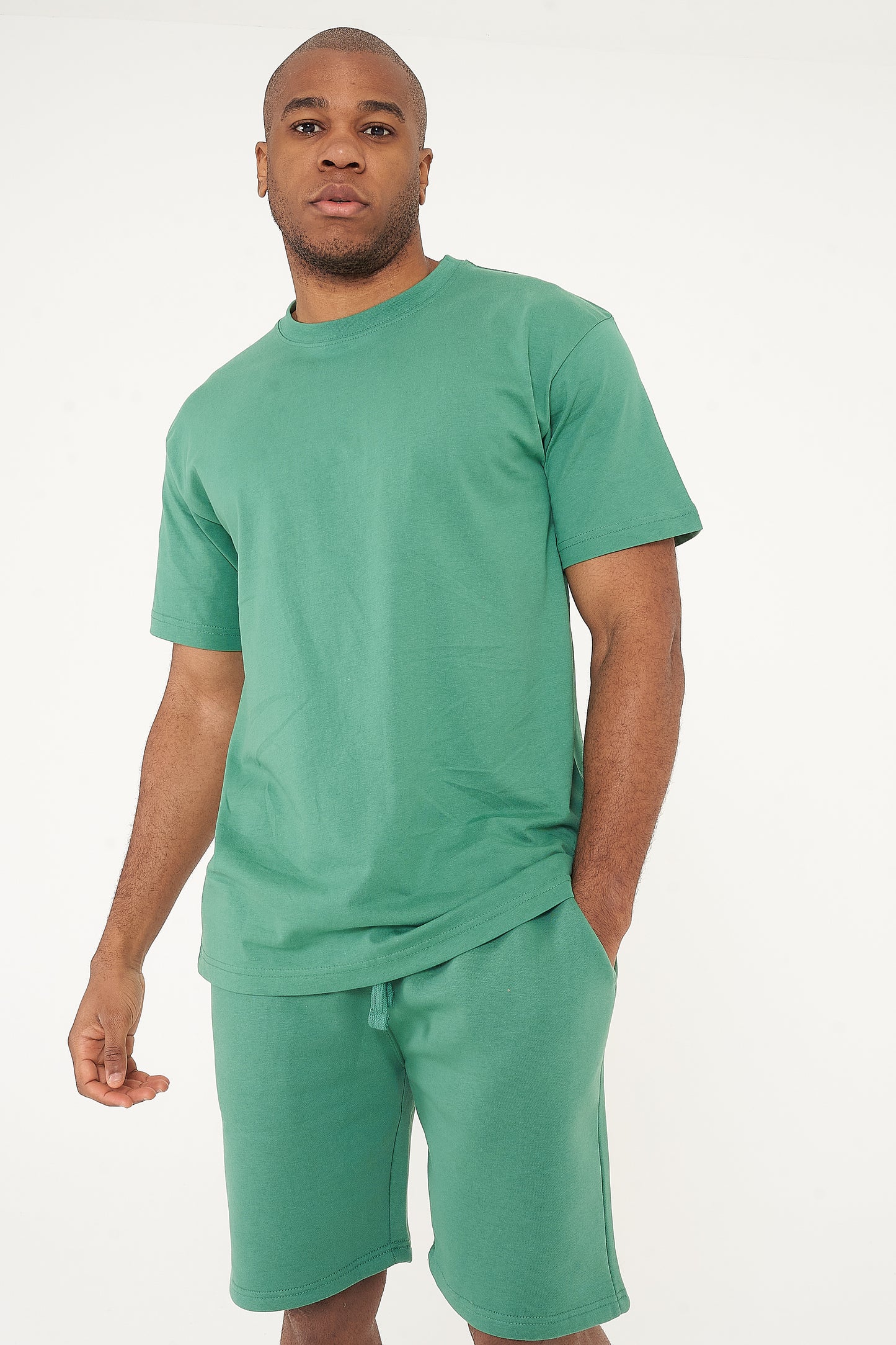 Side view of a male model in green oversized T-shirt and shorts, displaying relaxed fit - 365 Collection.
