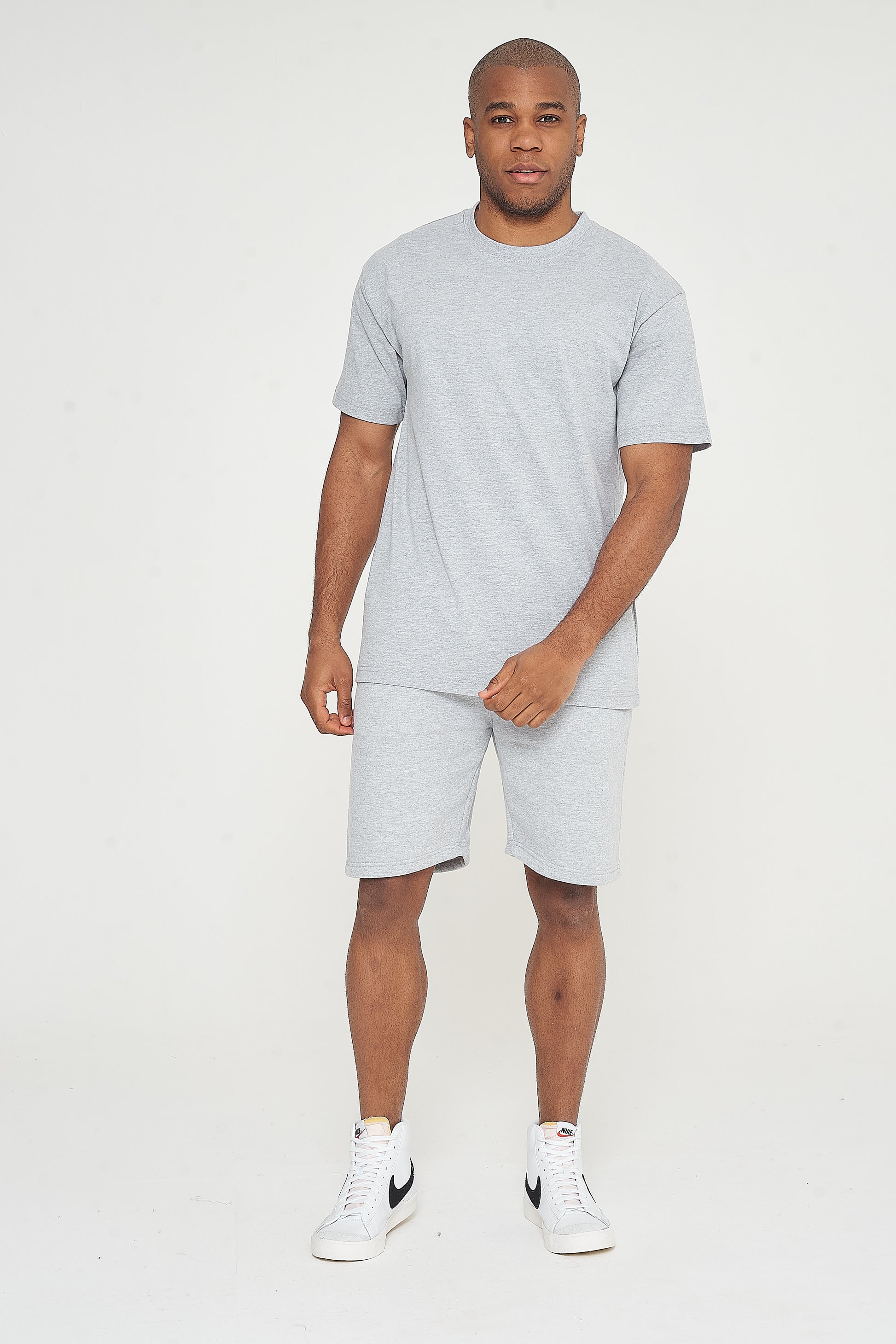 Upper body view of model wearing grey oversized T-shirt with hands clasped - 365 Collection.