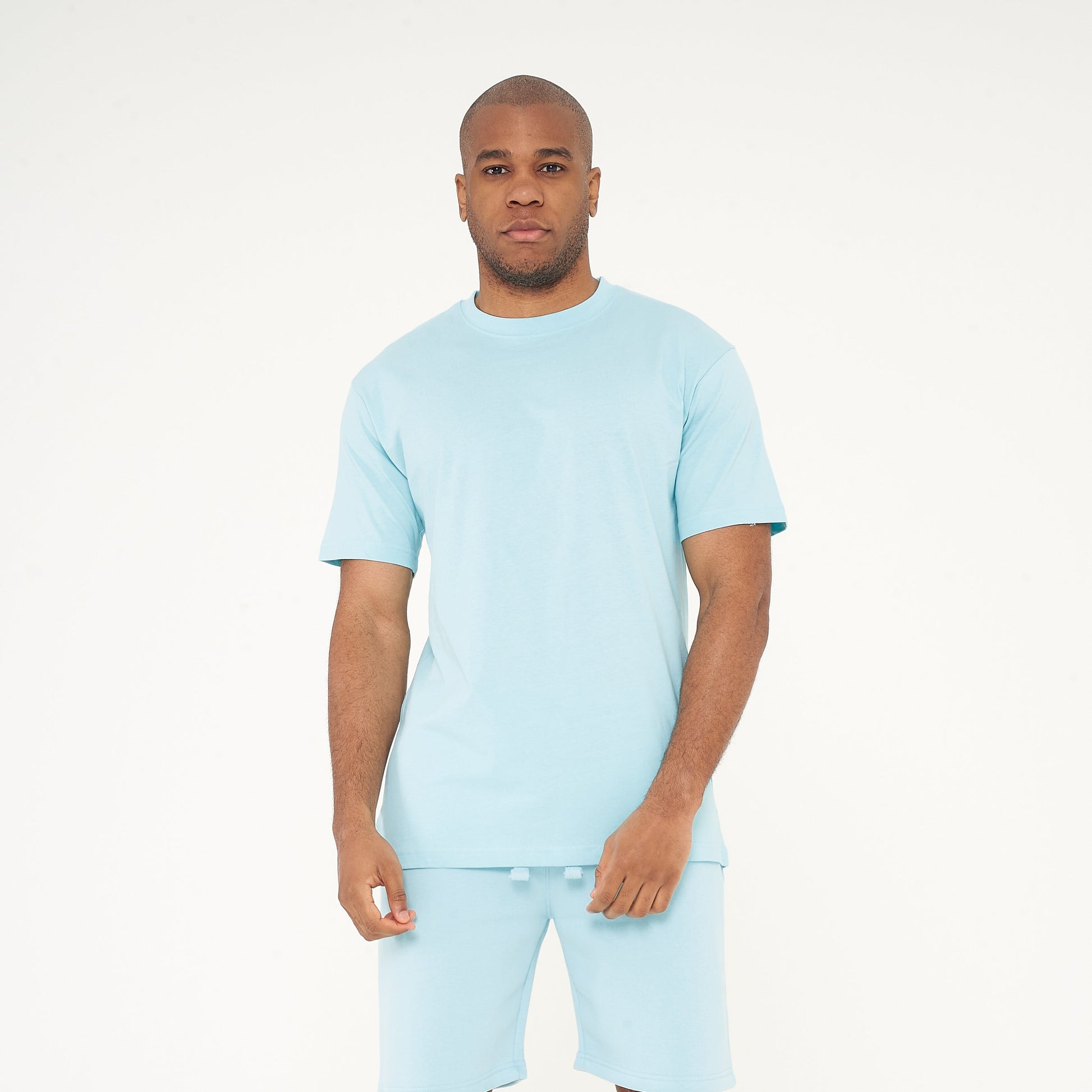 Model wearing men's turquoise oversized T-shirt from 365 Collection, full front body view. 