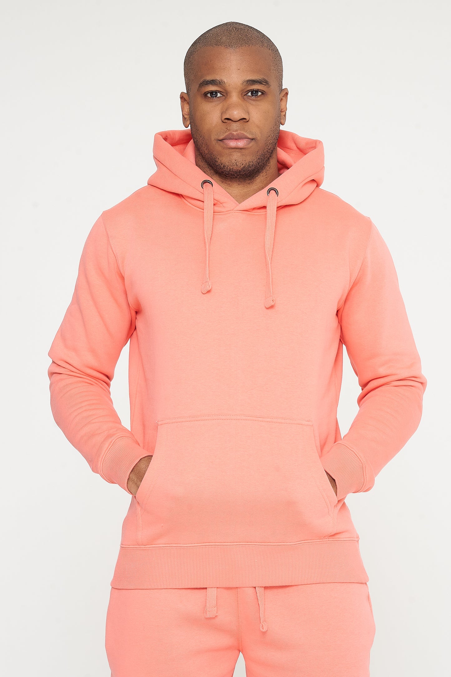 Male model standing, hands relaxed, in coral 365 Regular Hoodie and shorts – regular fit, 365 Collection.