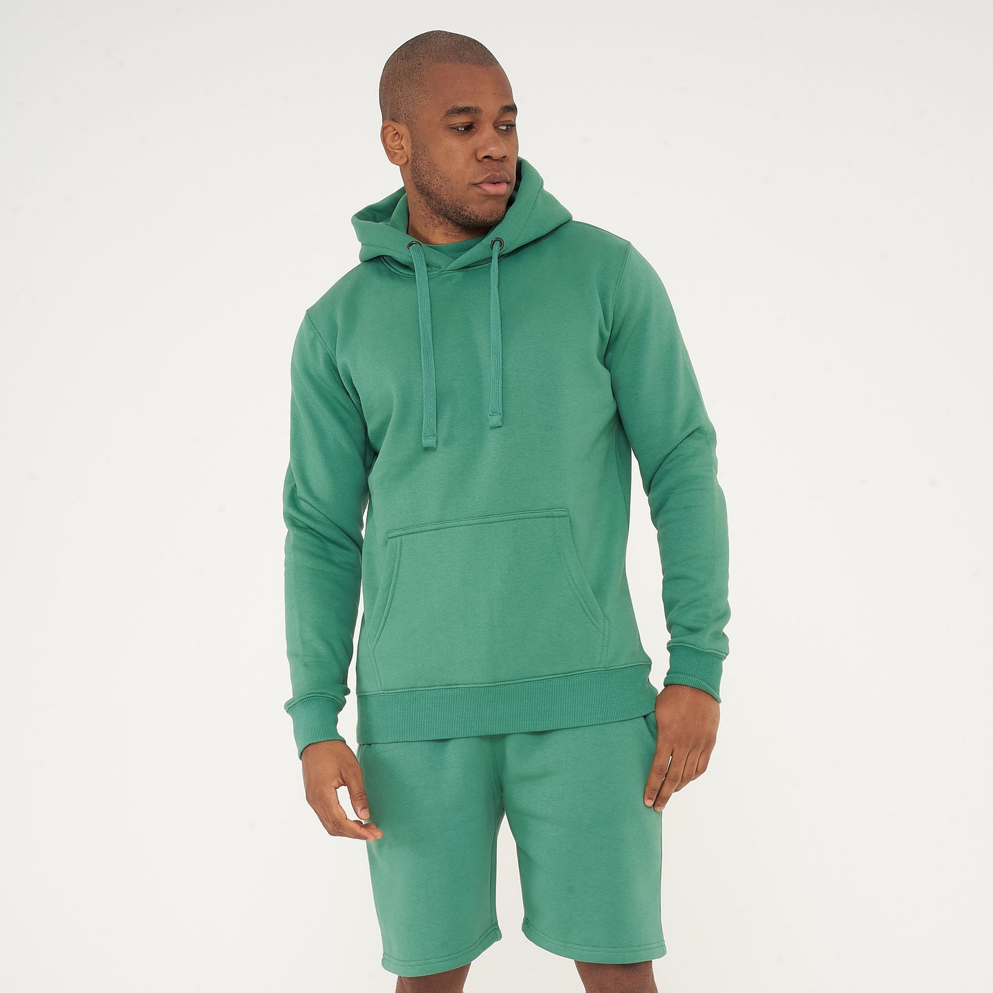Side view of male model wearing green regular fit hoodie and matching shorts – 365 Collection.