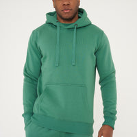Male model front view in green regular fit hoodie and shorts, hands at sides - 365 Collection.