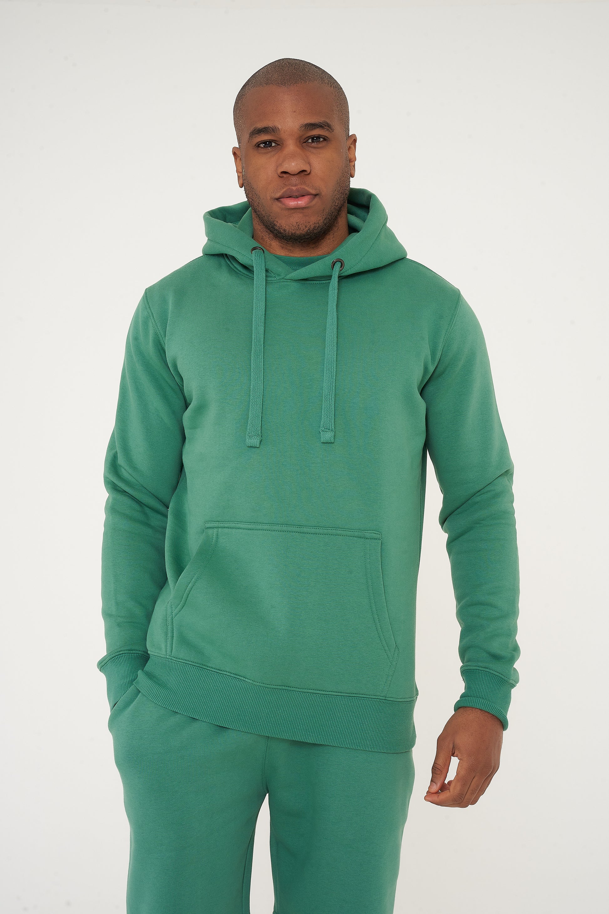 Male model front view in green regular fit hoodie and shorts, hands at sides - 365 Collection.