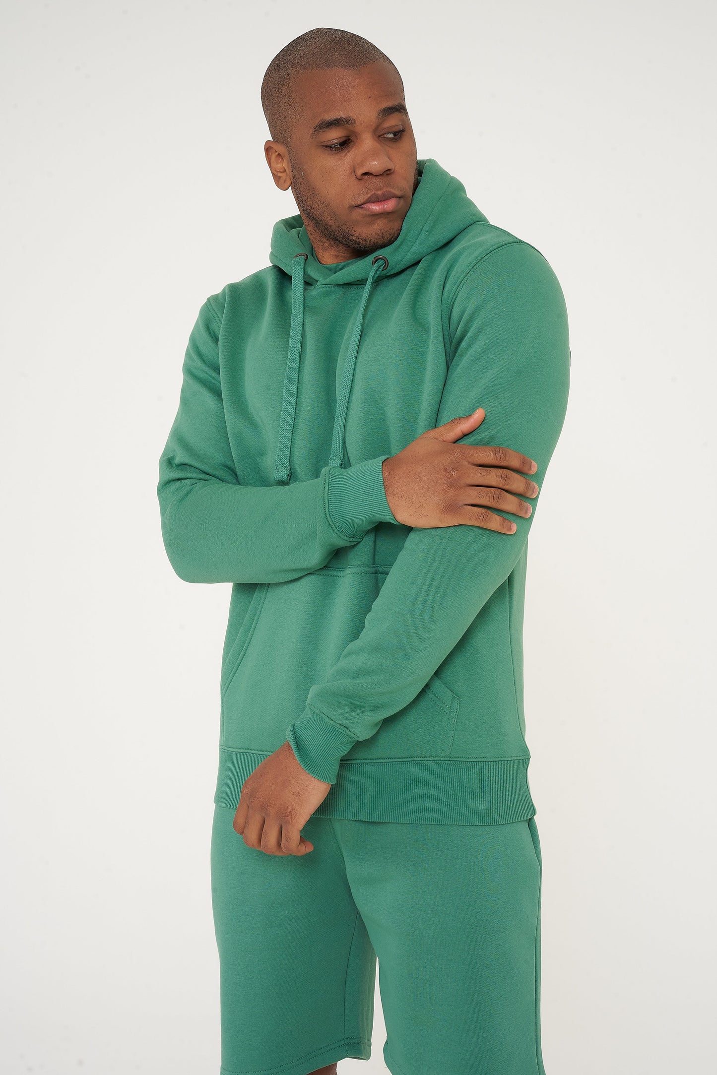 Male model adjusting the sleeve of green regular fit hoodie and shorts – 365 Collection.