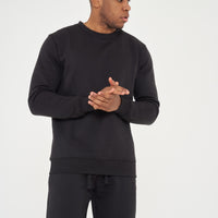 Male model front view wearing black 365 Regular Sweatshirt and matching shorts, hands clasped – regular fit, 365 Collection.