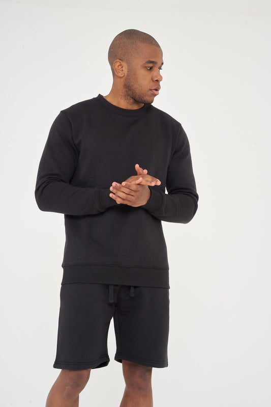 Male model front view wearing black 365 Regular Sweatshirt and matching shorts, hands clasped – regular fit, 365 Collection.