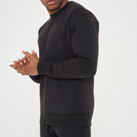 Male model side view wearing black 365 Regular Sweatshirt and shorts, hands clasped – regular fit, 365 Collection.