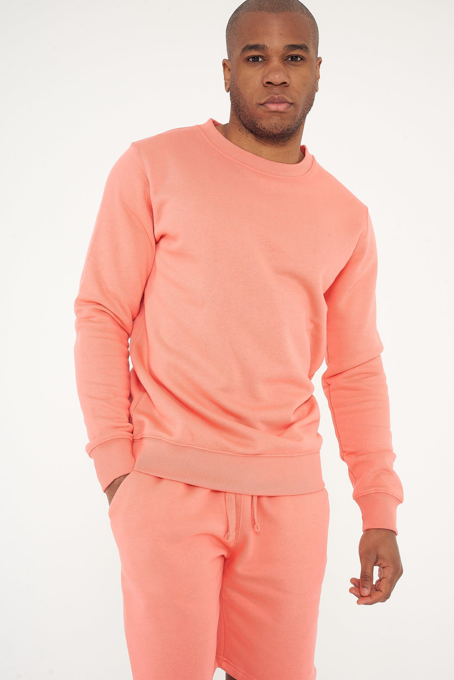 Male model standing in coral 365 Regular Sweatshirt and sweatpants, hands relaxed – 365 Collection – regular fit.