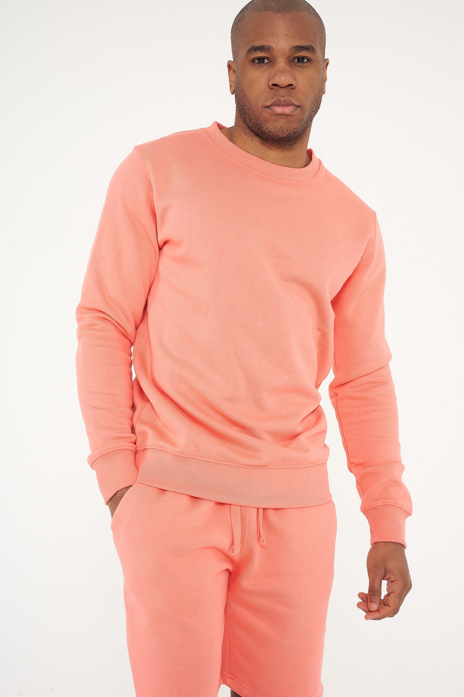 Male model standing in coral 365 Regular Sweatshirt and sweatpants, hands relaxed – 365 Collection – regular fit.