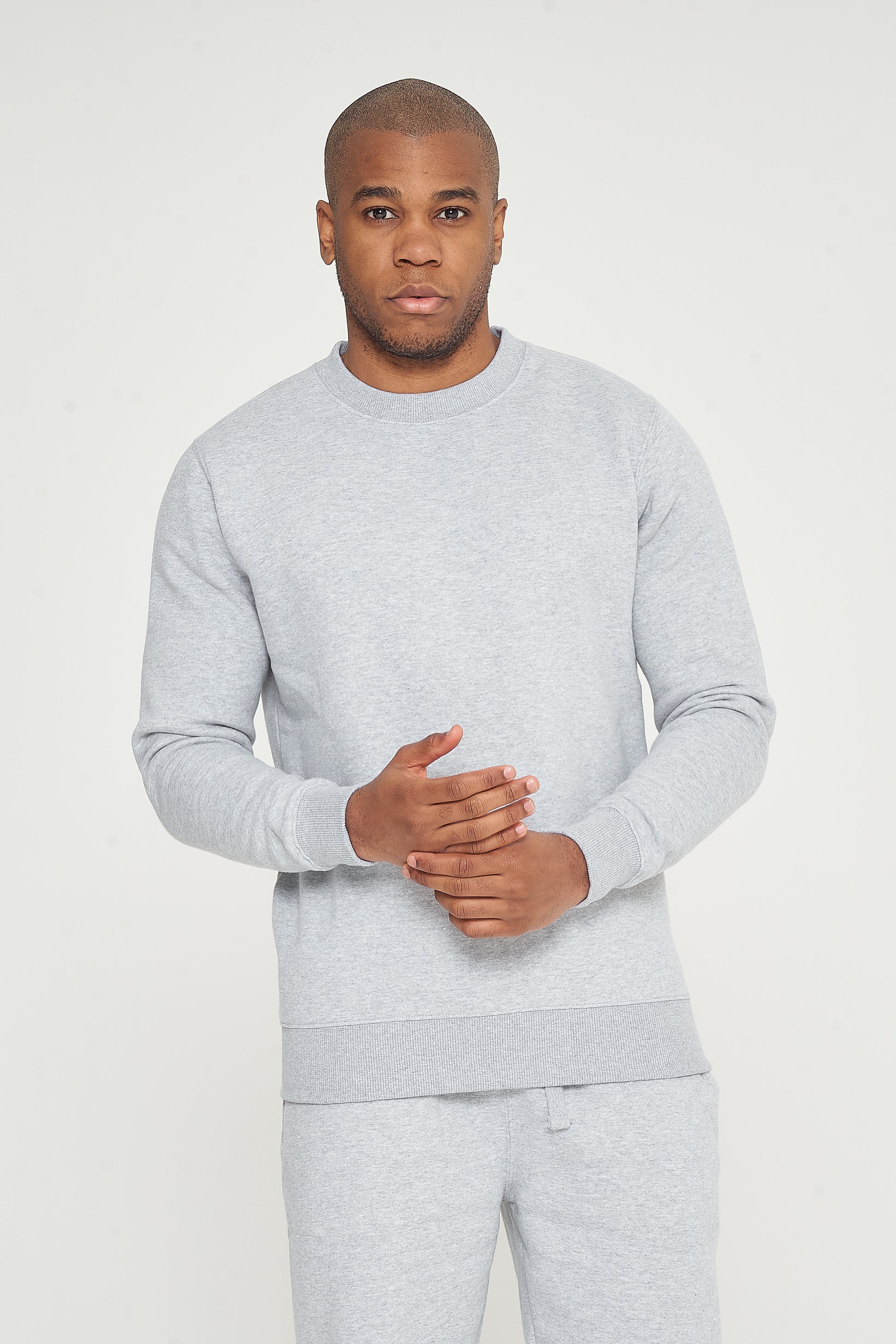 Model in grey regular-fit sweatshirt standing with fingers lightly gripping the other hand - 365 Collection.