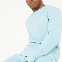 Model sitting and looking sideways in turquoise regular-fit sweatshirt - 365 Collection.