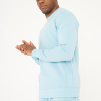 Model posing with clasped hands in a turquoise regular-fit sweatshirt - 365 Collection.