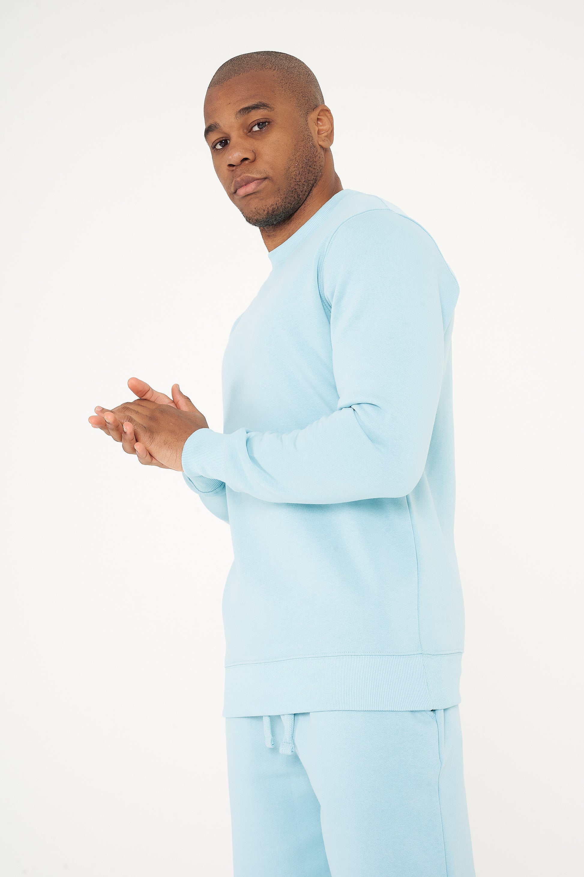 Model posing with clasped hands in a turquoise regular-fit sweatshirt - 365 Collection.