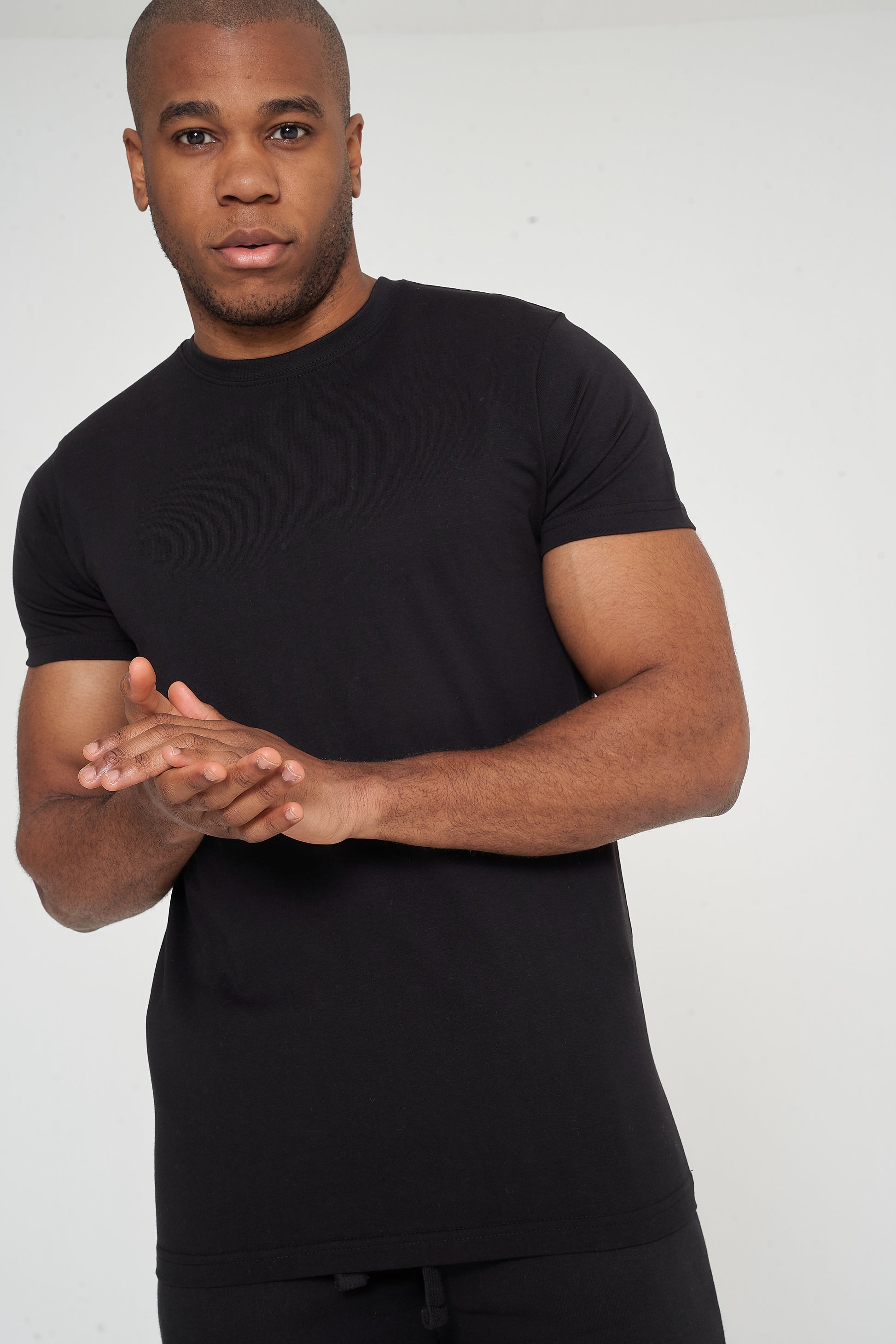 Male model adjusting sleeves in black 365 Regular T-shirt and shorts – regular fit, 365 Collection.