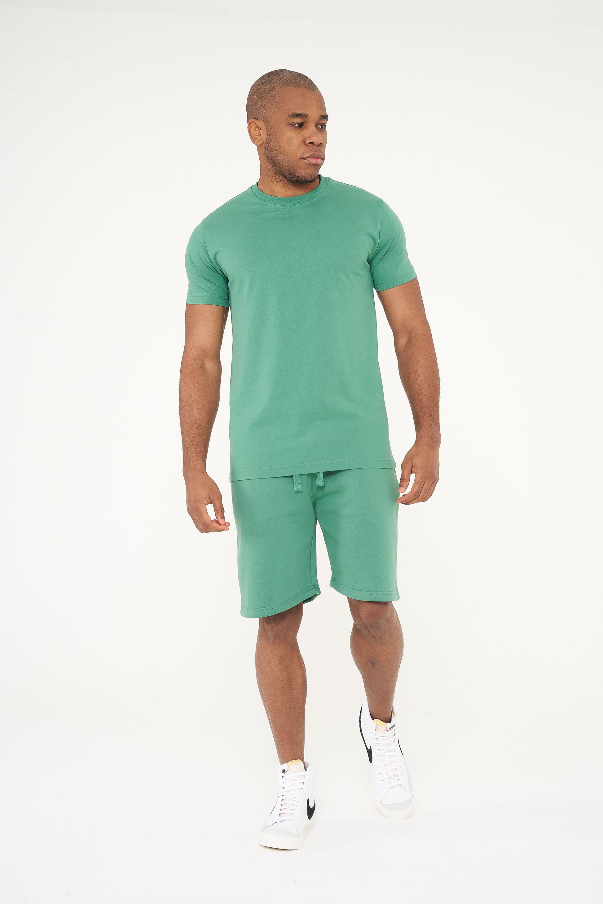 Side view of male model in green regular fit T-shirt and shorts, showing comfort and fit - 365 Collection.