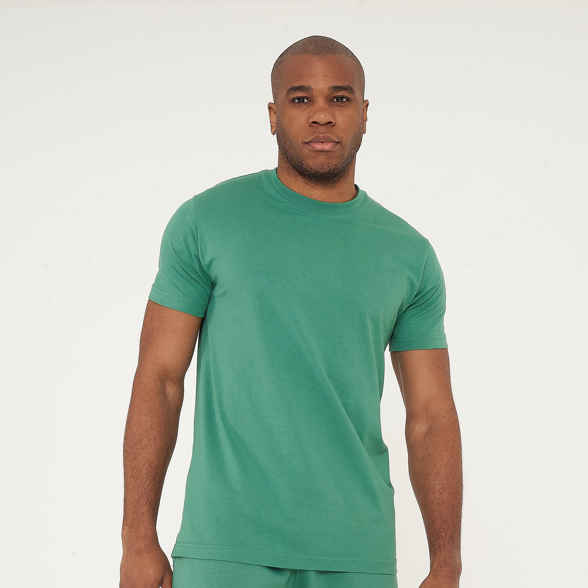 Front-facing model in green regular fit T-shirt and shorts, hands relaxed - 365 Collection.