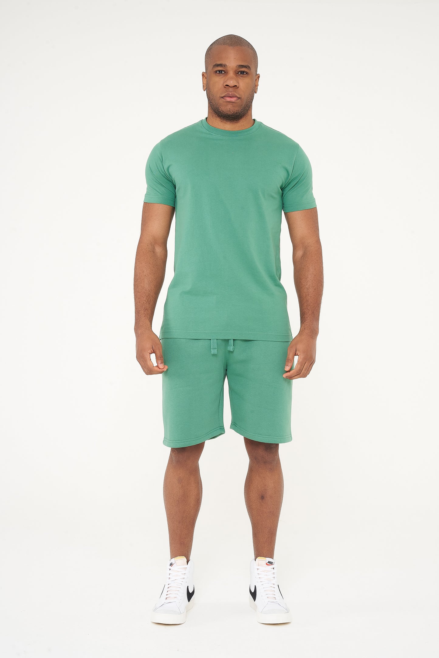 Full-body front view of a male model wearing a green regular fit T-shirt and matching shorts - 365 Collection.