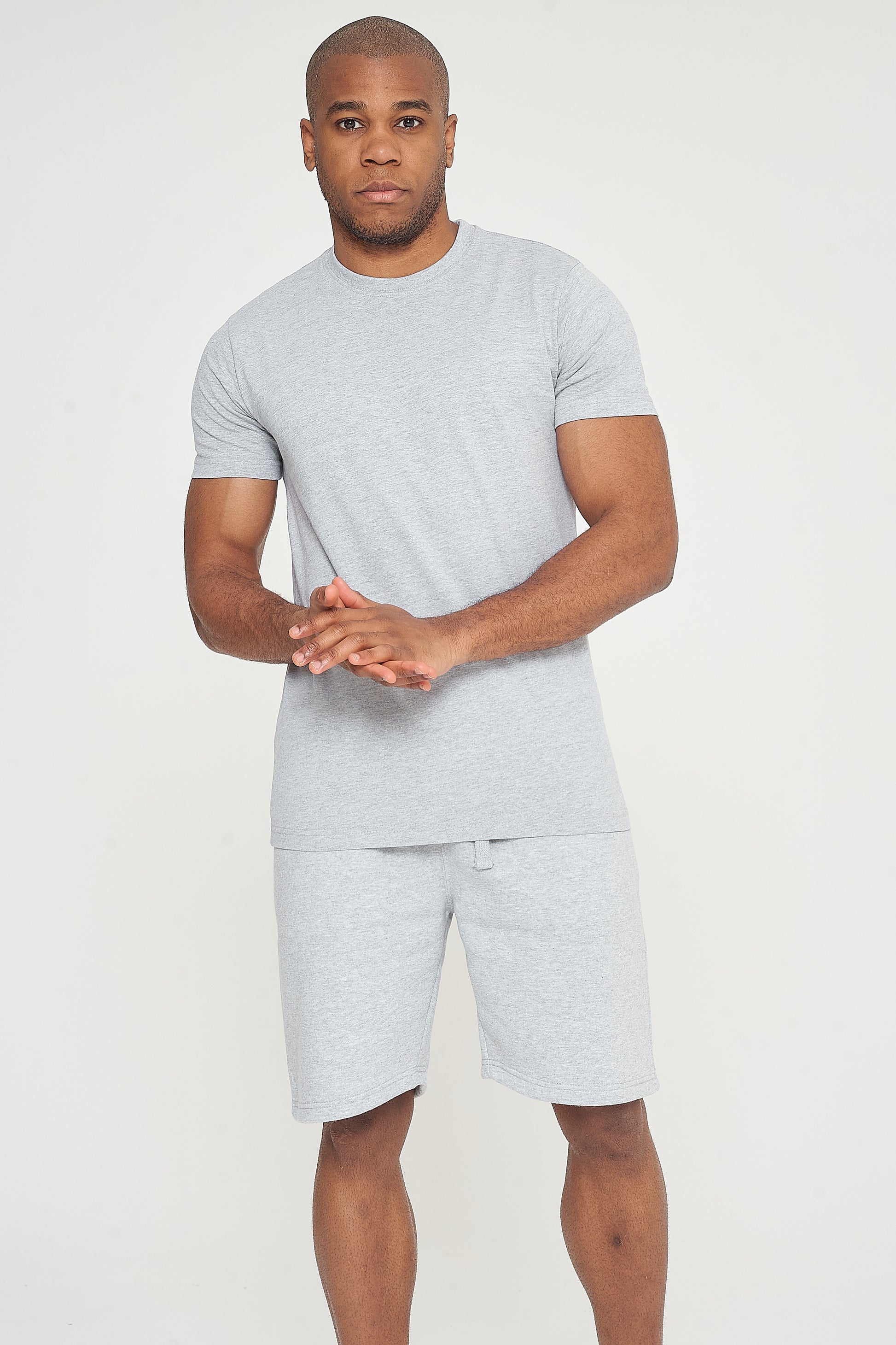 Model posing with hands clasped, wearing a grey regular-fit T-shirt - 365 Collection.