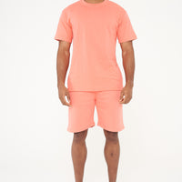 Male model side view wearing coral 365 fleece shorts and matching T-shirt – relaxed fit, 365 Collection. 