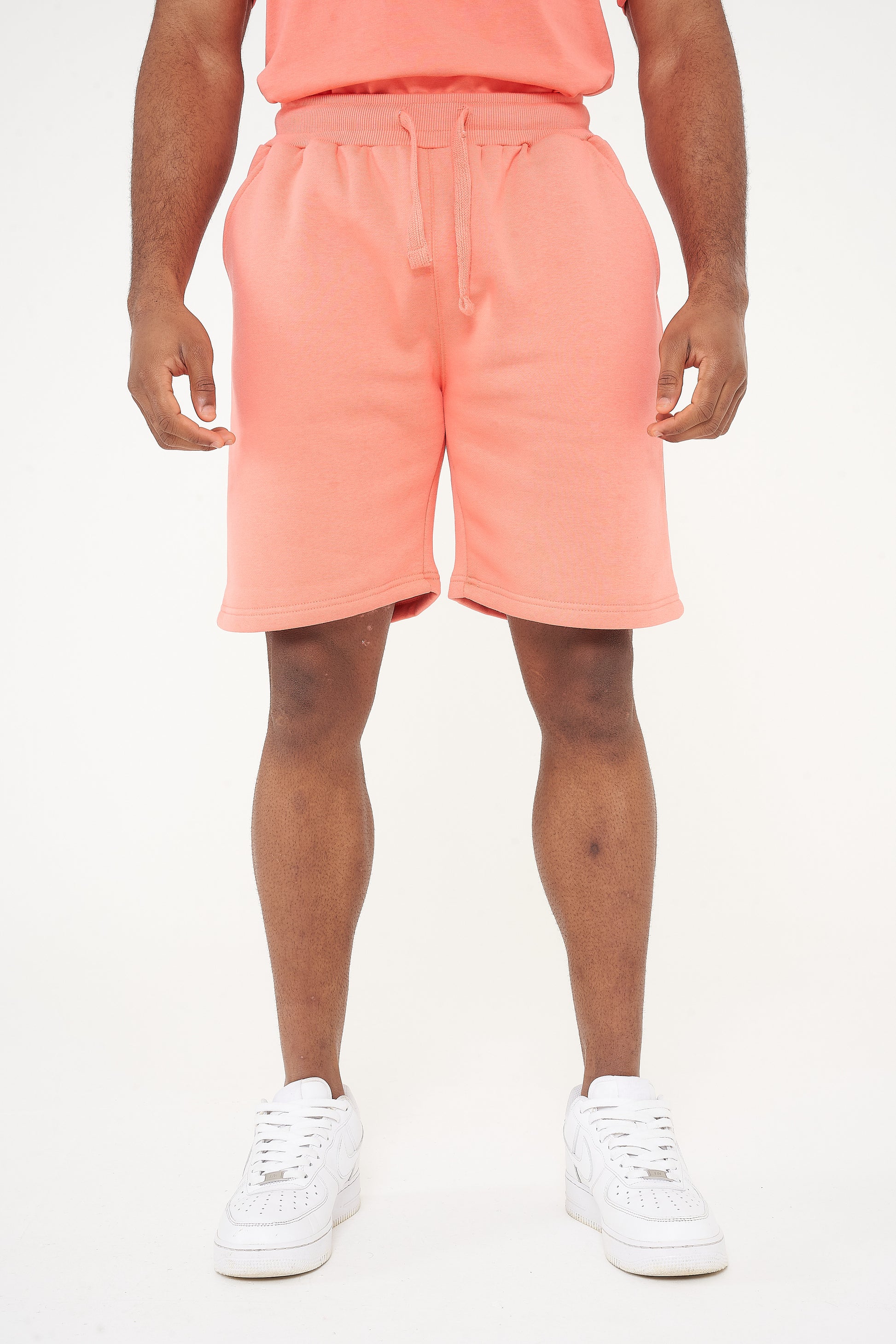 Male model front view wearing coral 365 fleece shorts and matching T-shirt – relaxed fit, 365 Collection. 