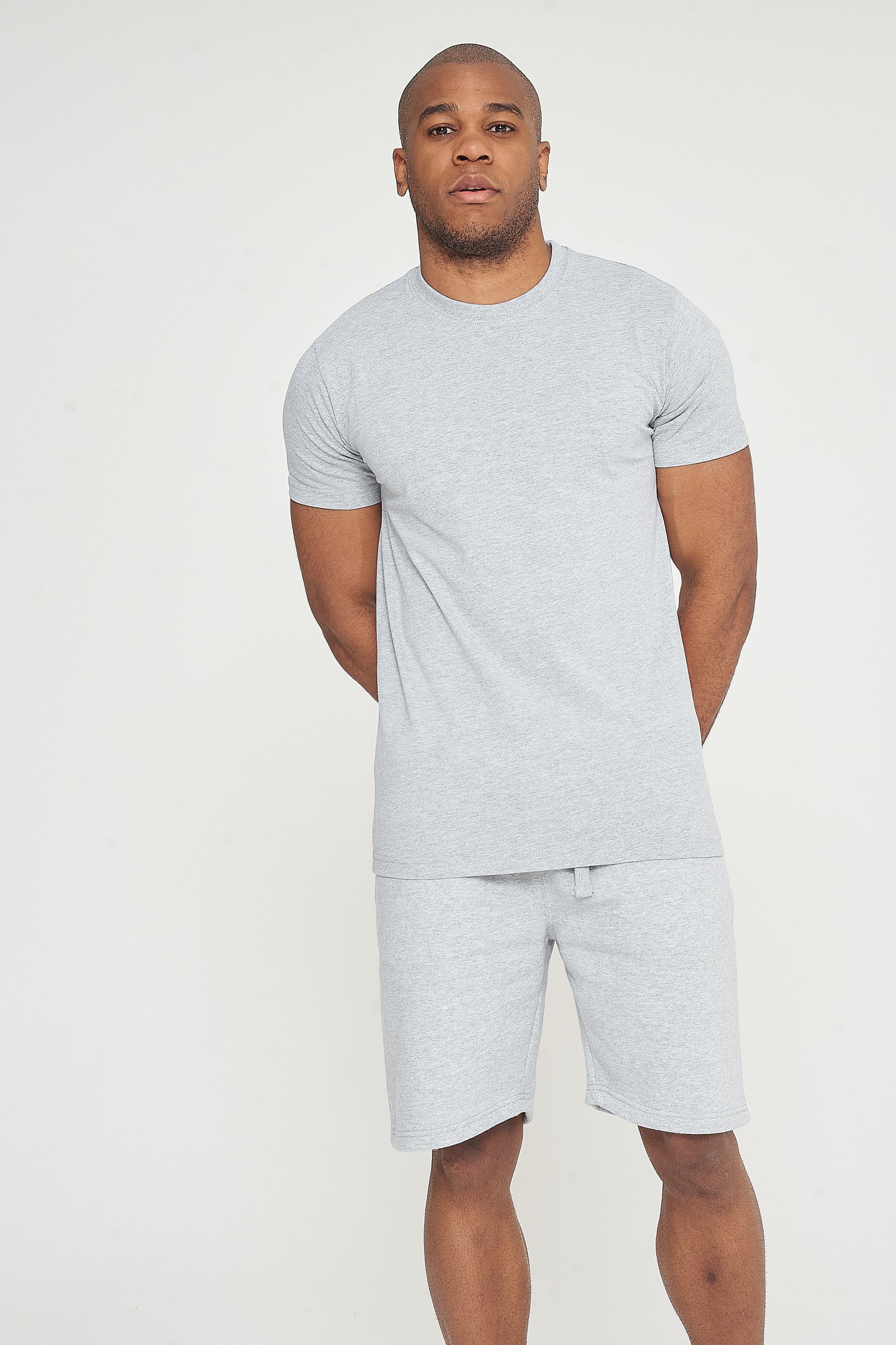 Model standing front view wearing grey regular-fit shorts with a matching T-shirt – 365 Collection.