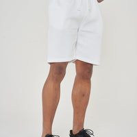 Model wearing men's white shorts from waist to feet with hands clasped, 365 Collection.